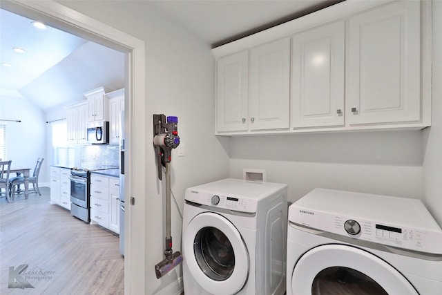 laundry room featuring cabinets, light hardwood / wood-style flooring, and washer and clothes dryer