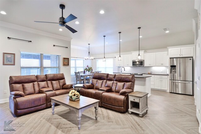 living room featuring crown molding, plenty of natural light, light parquet floors, and ceiling fan with notable chandelier