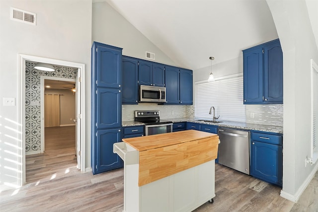 kitchen featuring blue cabinetry, butcher block counters, sink, decorative light fixtures, and stainless steel appliances