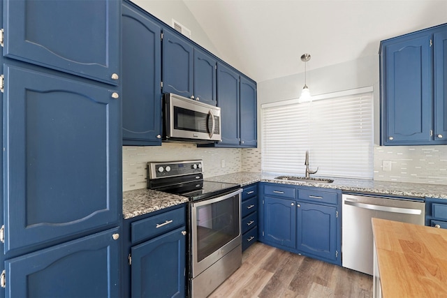 kitchen featuring appliances with stainless steel finishes, blue cabinets, sink, hanging light fixtures, and hardwood / wood-style flooring