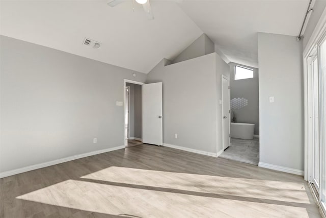 unfurnished bedroom featuring wood-type flooring, high vaulted ceiling, and ensuite bath