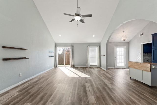 unfurnished living room with hardwood / wood-style flooring, high vaulted ceiling, and ceiling fan with notable chandelier