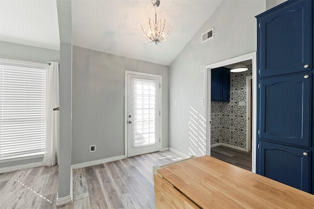 foyer featuring light hardwood / wood-style floors, vaulted ceiling, and a notable chandelier