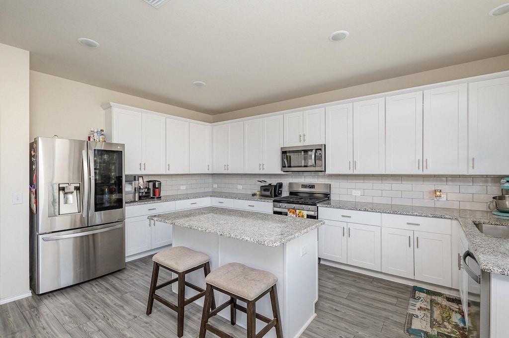 kitchen featuring white cabinetry, a kitchen bar, a kitchen island, and appliances with stainless steel finishes