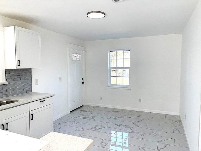 kitchen with white cabinetry, sink, and backsplash