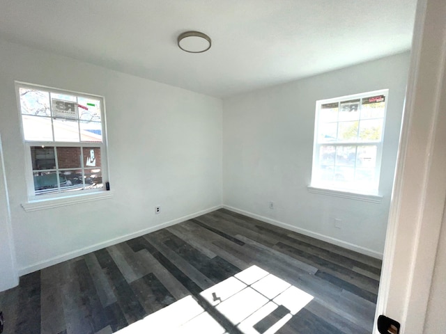 spare room featuring dark wood-type flooring and a healthy amount of sunlight