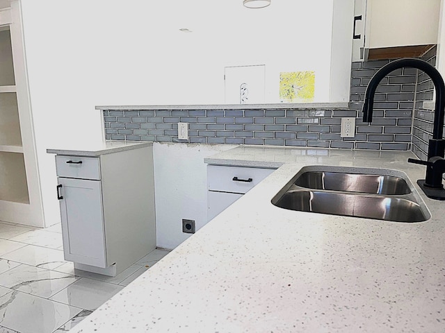 kitchen featuring white cabinetry, sink, tasteful backsplash, and light stone countertops