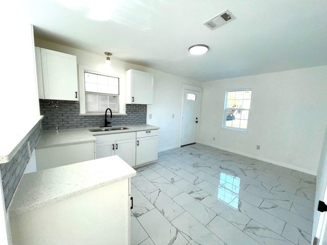 kitchen featuring white cabinetry, sink, and tasteful backsplash