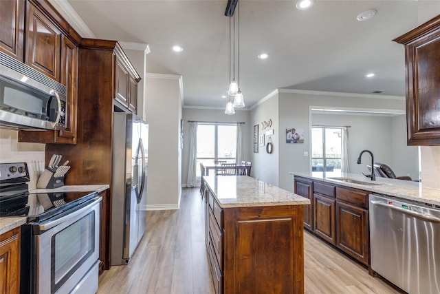 kitchen with sink, a center island, stainless steel appliances, light hardwood / wood-style flooring, and decorative light fixtures