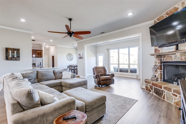 living room featuring a fireplace, hardwood / wood-style flooring, ceiling fan, and ornamental molding