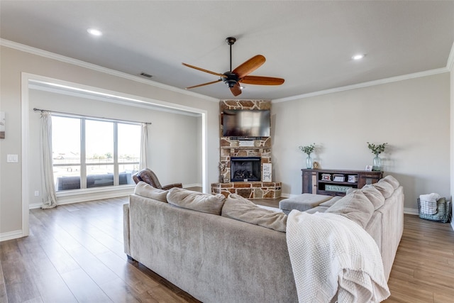 living room with a fireplace, hardwood / wood-style floors, ceiling fan, and crown molding