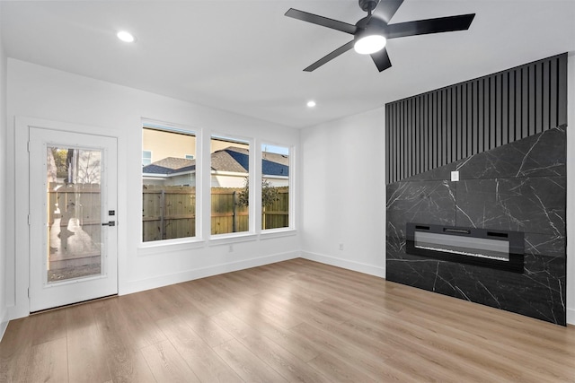 unfurnished living room with ceiling fan, tile walls, and hardwood / wood-style flooring