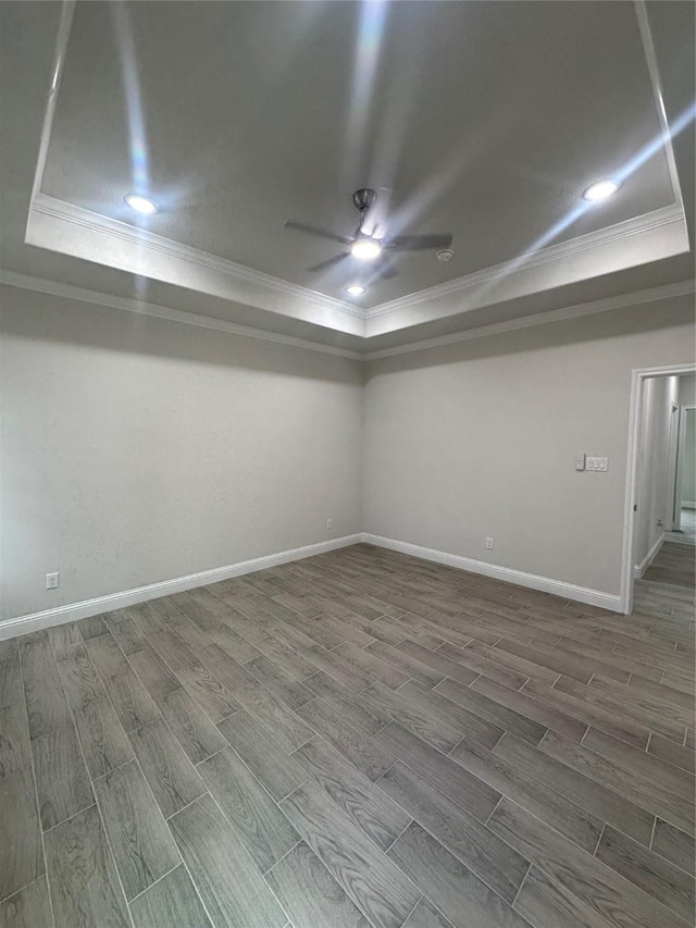 empty room featuring a tray ceiling, ceiling fan, and ornamental molding