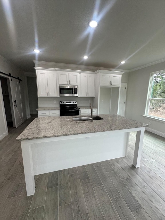 kitchen with a kitchen island with sink, sink, a barn door, white cabinets, and black range with electric stovetop