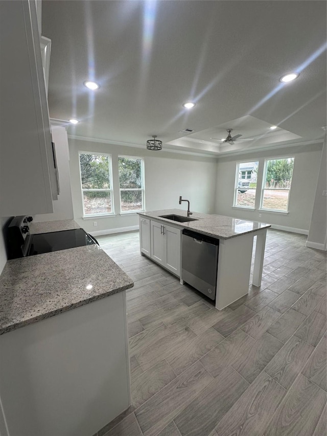 kitchen featuring dishwasher, white cabinets, a raised ceiling, range with electric stovetop, and an island with sink