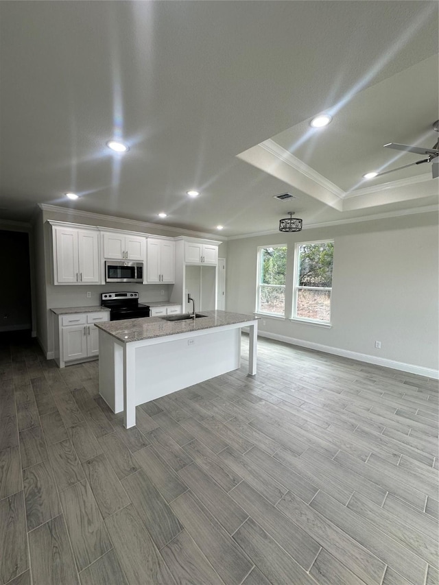 kitchen featuring a raised ceiling, a kitchen island with sink, crown molding, electric range, and white cabinetry