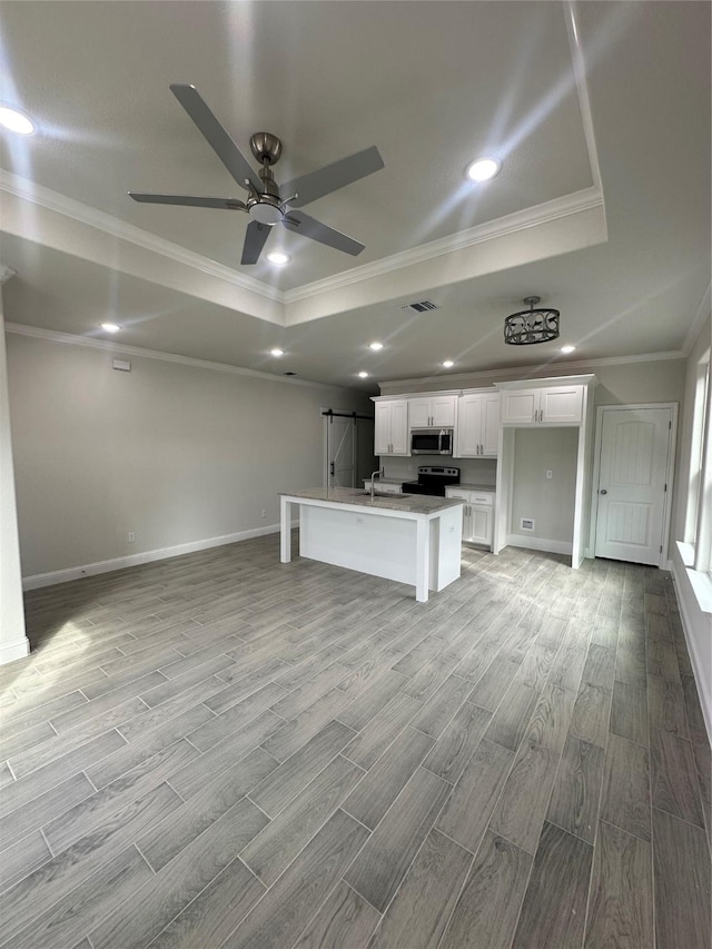 unfurnished living room with ceiling fan, light hardwood / wood-style floors, ornamental molding, and a tray ceiling