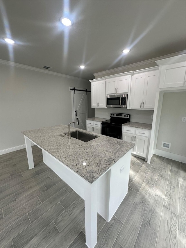 kitchen featuring electric range, a barn door, white cabinets, and a kitchen island with sink