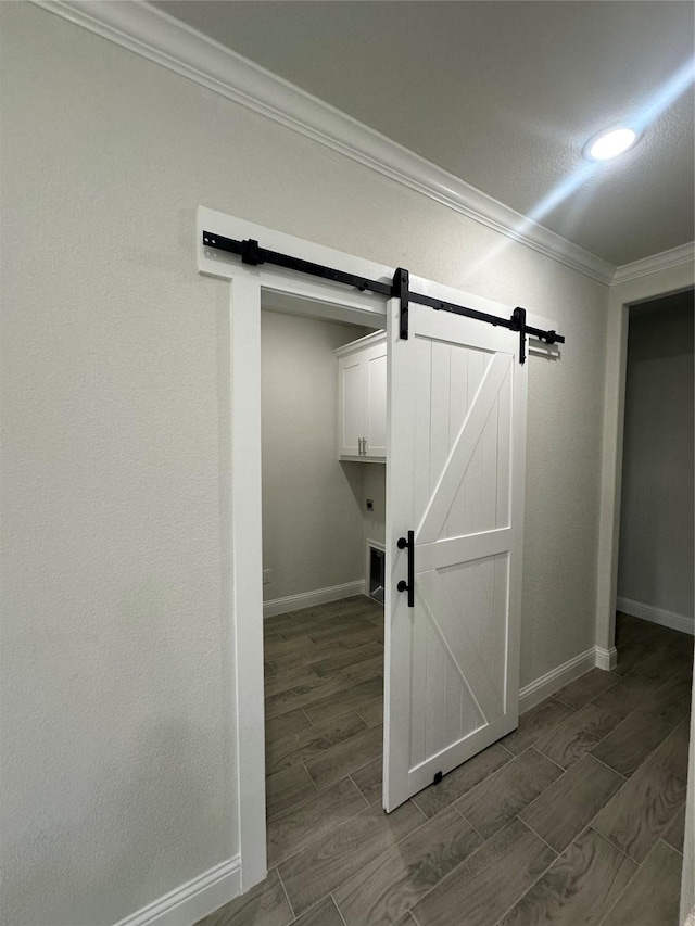 washroom featuring a barn door, cabinets, and ornamental molding