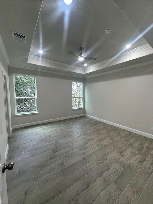 empty room with hardwood / wood-style floors, a raised ceiling, ceiling fan, and ornamental molding