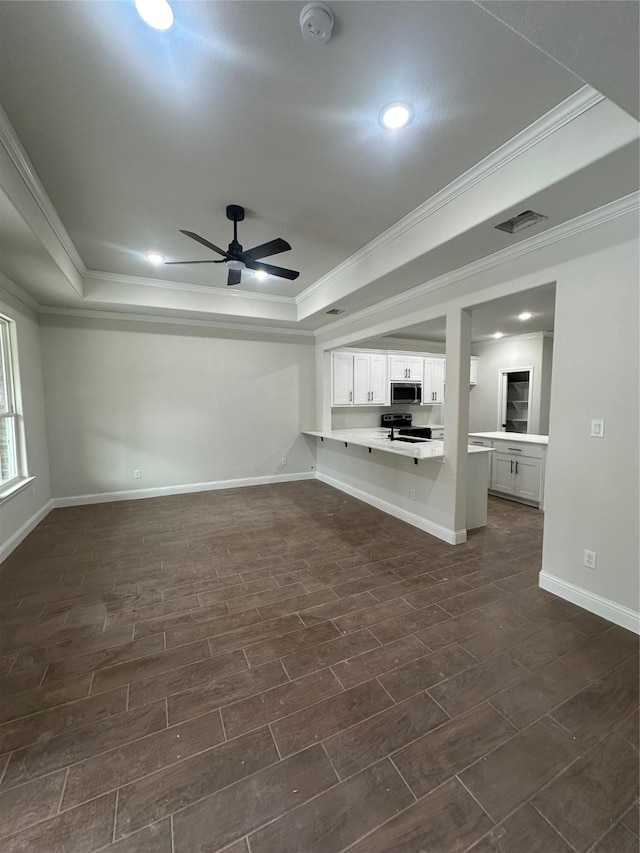 unfurnished living room featuring ceiling fan, a raised ceiling, and ornamental molding