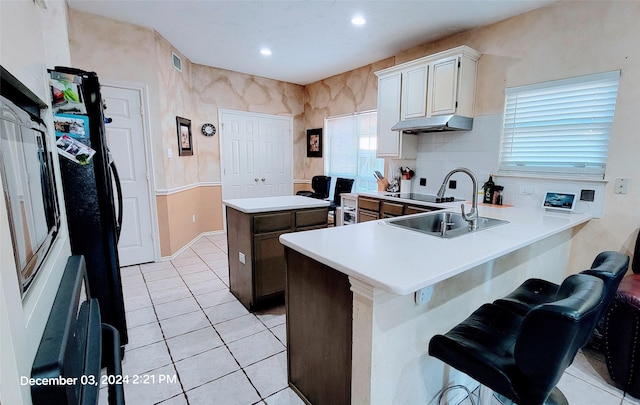 kitchen with white cabinetry, sink, a kitchen breakfast bar, light tile patterned floors, and kitchen peninsula