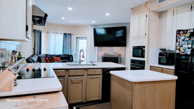 kitchen with sink, range hood, decorative backsplash, a center island with sink, and black appliances