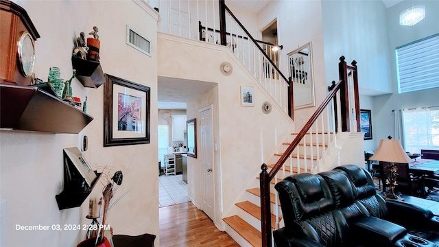 staircase featuring a towering ceiling and wood-type flooring