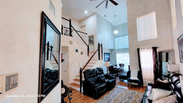 living room featuring ceiling fan, light hardwood / wood-style floors, and a high ceiling