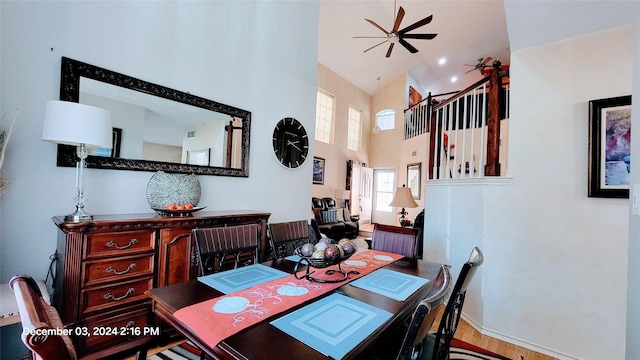 dining room with ceiling fan, hardwood / wood-style floors, and a high ceiling