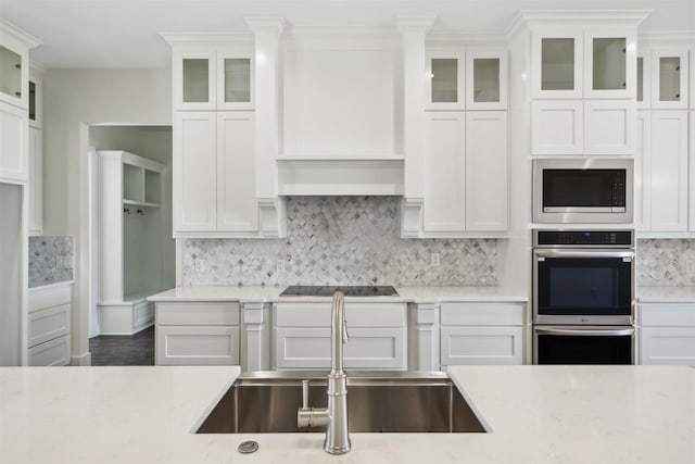 kitchen featuring light stone countertops, white cabinetry, sink, stainless steel appliances, and tasteful backsplash