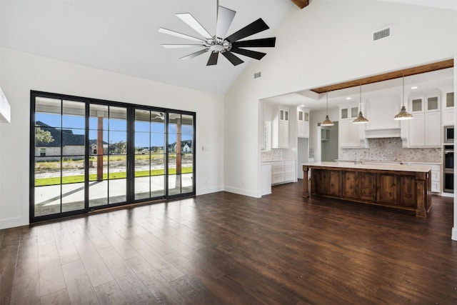 unfurnished living room featuring dark wood-type flooring, high vaulted ceiling, sink, ceiling fan, and beamed ceiling