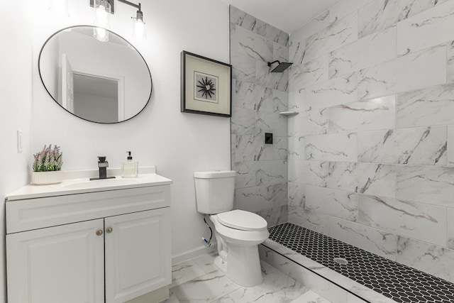 bathroom with a tile shower, vanity, and toilet