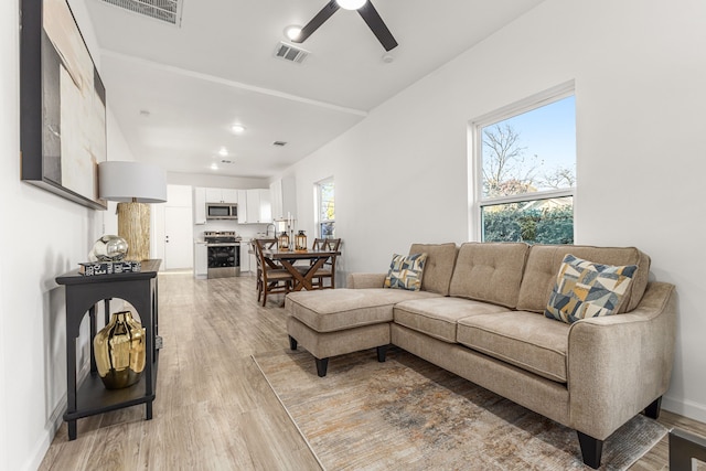 living room featuring plenty of natural light, light hardwood / wood-style floors, sink, and ceiling fan