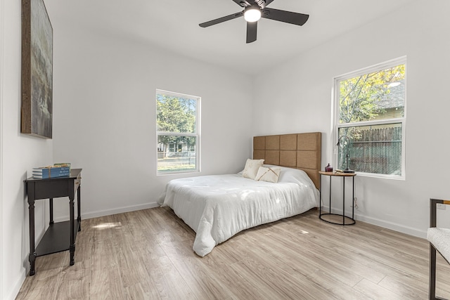 bedroom featuring ceiling fan, light hardwood / wood-style floors, and multiple windows