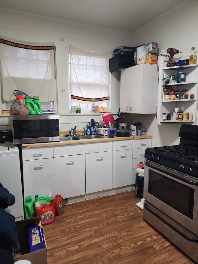 kitchen with appliances with stainless steel finishes, crown molding, washer / dryer, dark hardwood / wood-style floors, and white cabinetry