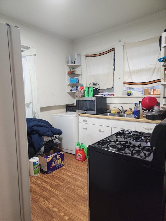 kitchen with refrigerator, ornamental molding, sink, black range, and light hardwood / wood-style floors