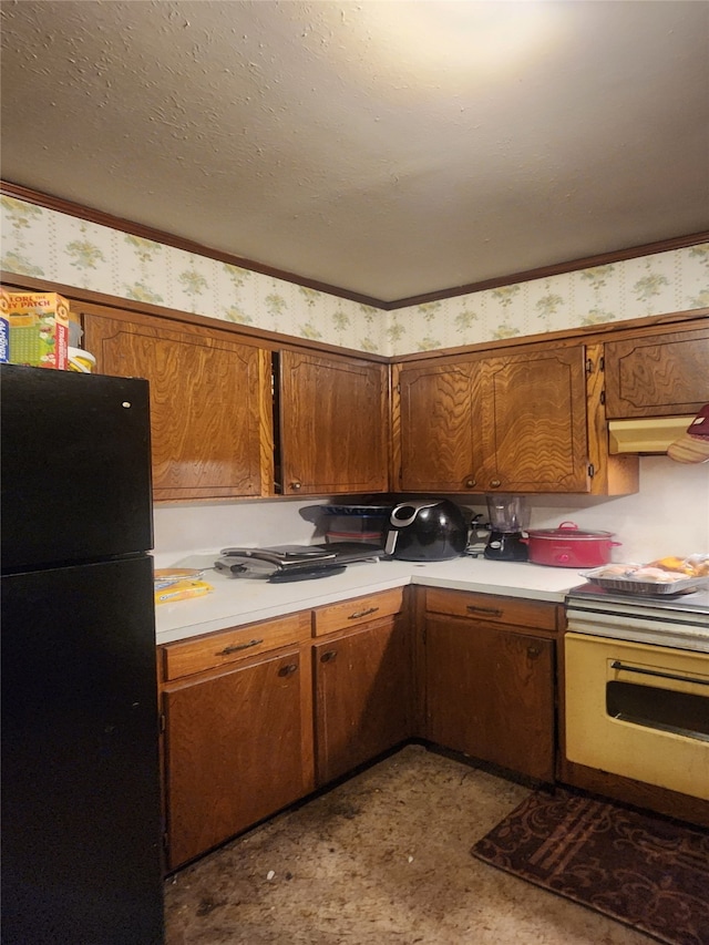 kitchen with black refrigerator, range, and a textured ceiling