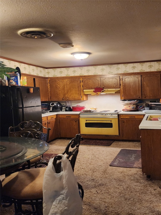 kitchen featuring black refrigerator, range, and a textured ceiling