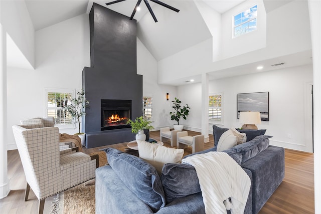 living room featuring hardwood / wood-style floors, a large fireplace, high vaulted ceiling, and plenty of natural light