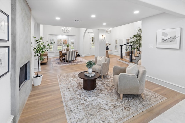 living room with a high end fireplace, light hardwood / wood-style floors, and a chandelier