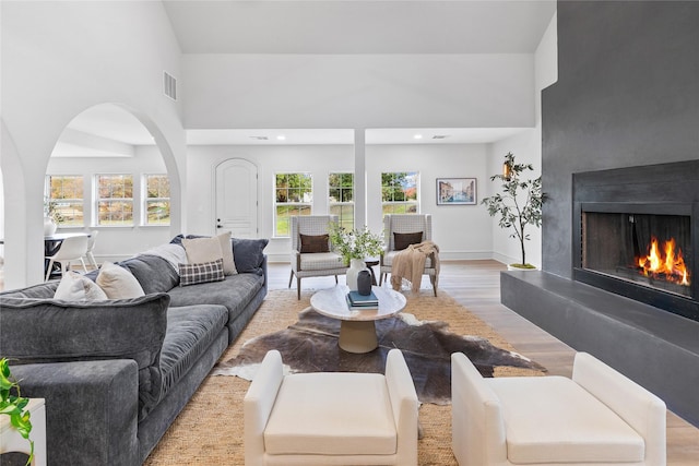 living room with plenty of natural light, high vaulted ceiling, and light wood-type flooring