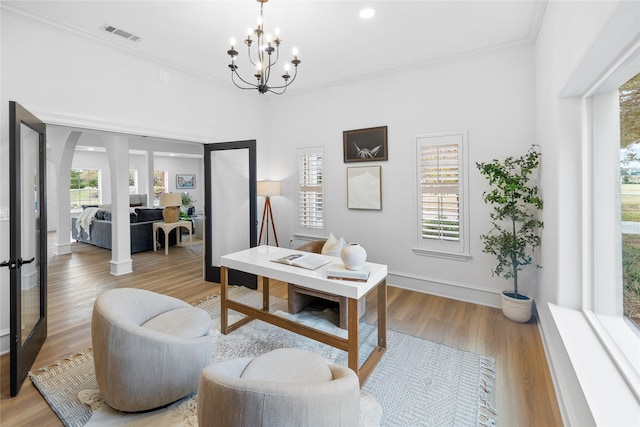 living room featuring a wealth of natural light, an inviting chandelier, ornamental molding, and light wood-type flooring