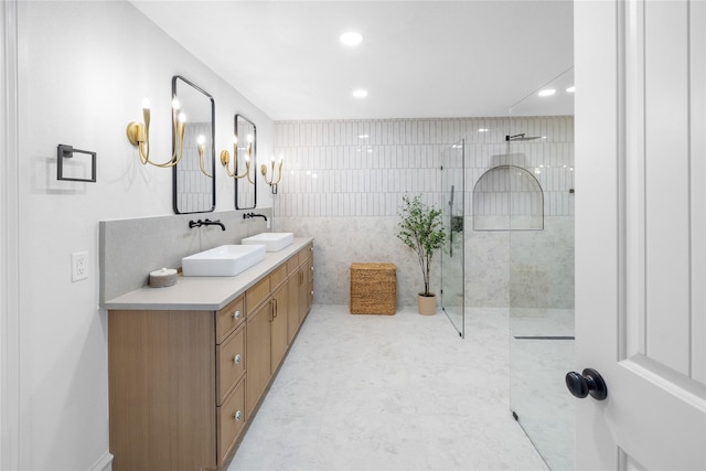 bathroom featuring vanity, tiled shower, and tile walls