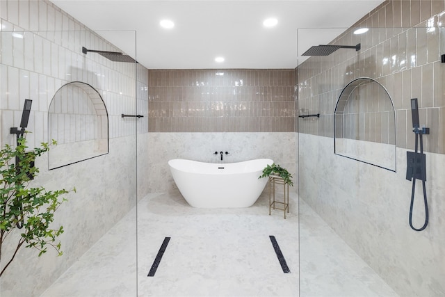 bathroom with tile walls and shower with separate bathtub