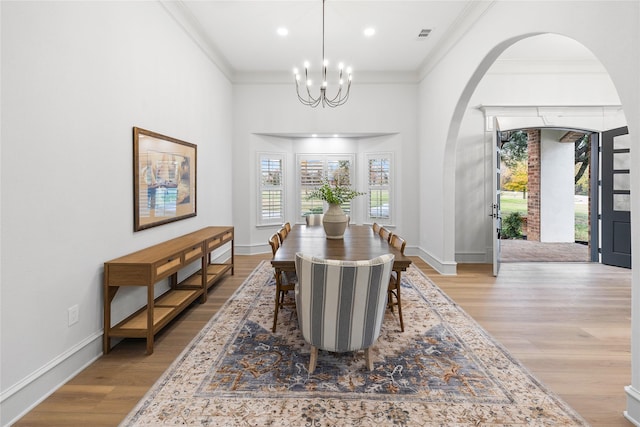 dining space with light hardwood / wood-style floors, an inviting chandelier, and ornamental molding