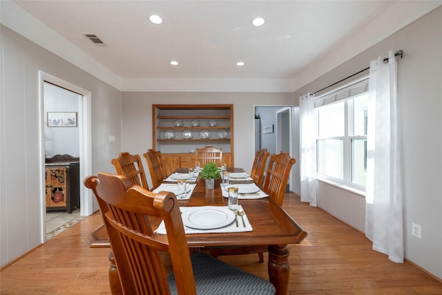 dining room with built in shelves and light hardwood / wood-style flooring