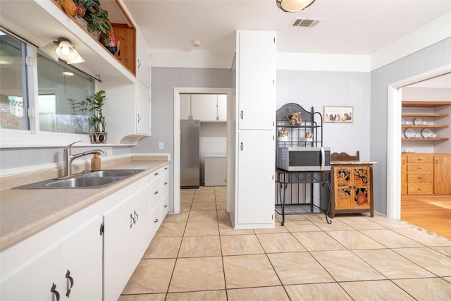 kitchen featuring light tile patterned flooring, white cabinetry, and sink