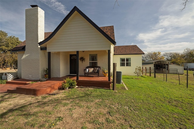 back of property with a yard and central AC