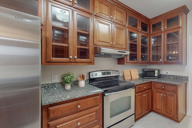 kitchen with light tile patterned flooring, stainless steel appliances, and dark stone countertops